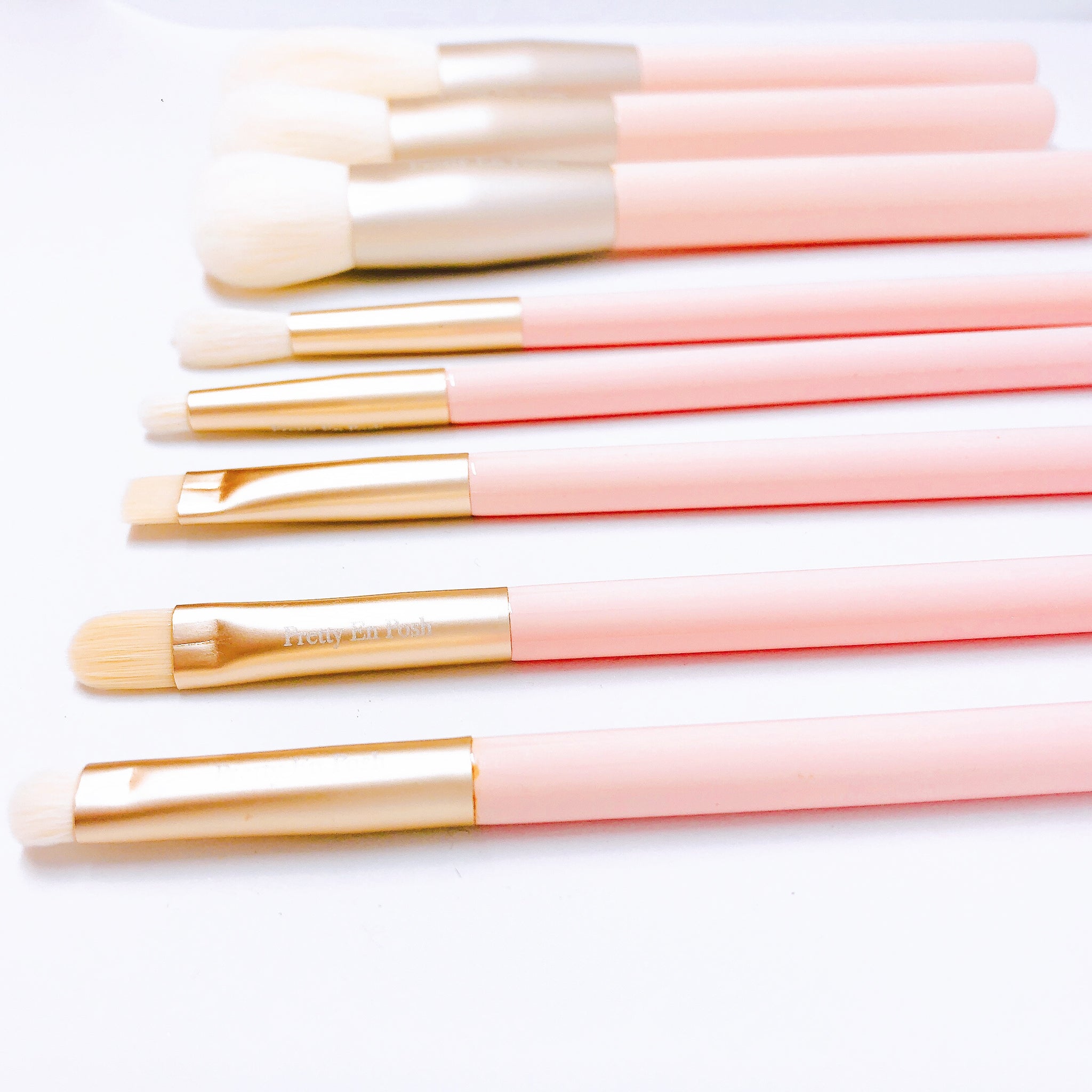 Makeup brush set with white bristles, gold accents and pink handle.