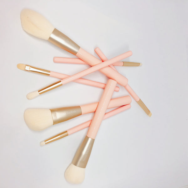 Makeup brush set with white bristles, gold accents and pink handle.